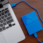A blue external drive attached to a MacBook.
