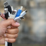 A hand gripping a large number of USB cords.