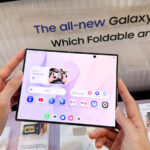 A Galaxy Z Fold8 in a person's hands at an event with promo materials around.