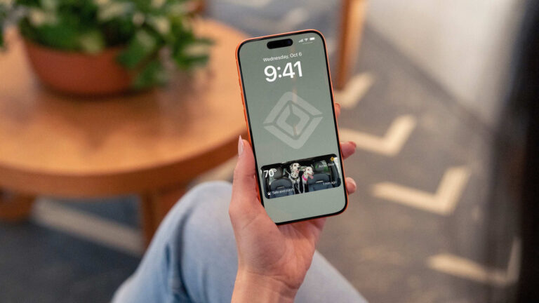Photo of a hand holding a smartphone displaying the Rivian Pet Cam active on the lock screen.