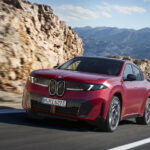 BMW's new iX4 in Euro trim shown in red on a twisty mountain road
